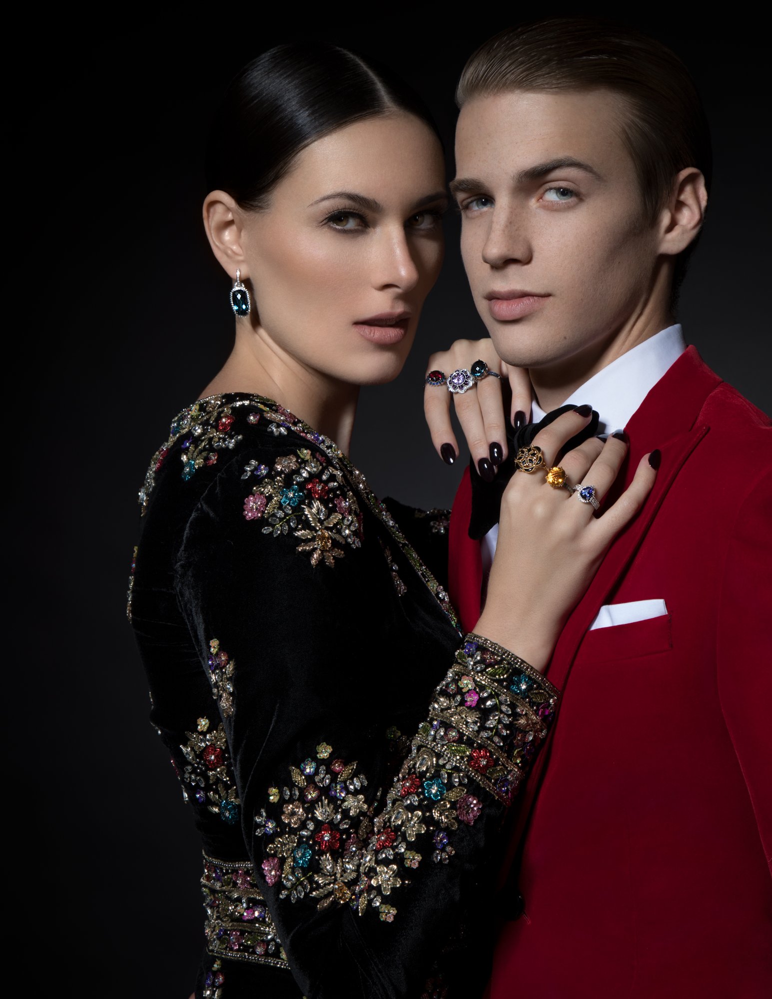 Model wearing blue topaz drop earrings and gemstone cocktail rings with embroidered velvet evening gown